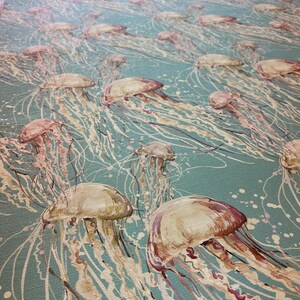 May include: A teal blue background with a pattern of beige and pink jellyfish. The jellyfish have long, flowing tentacles.