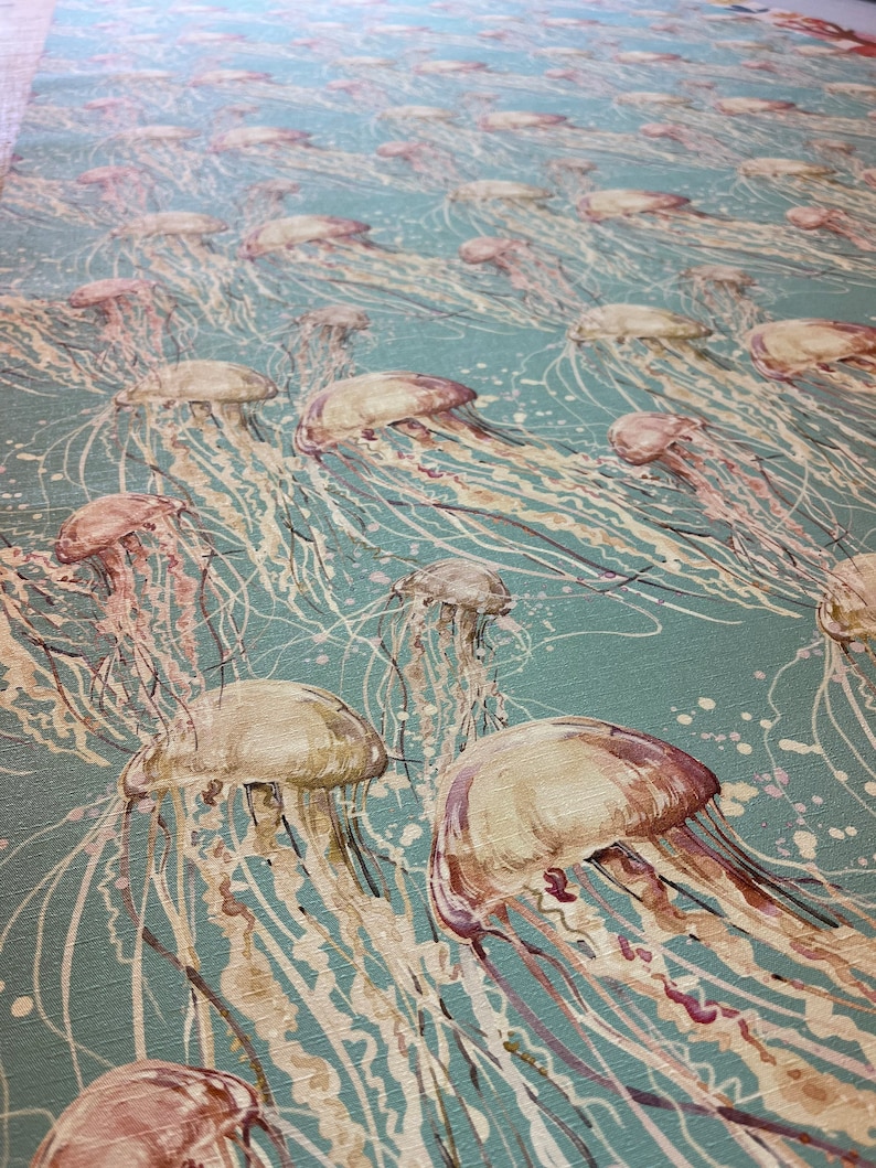 May include: A teal blue background with a pattern of beige and pink jellyfish. The jellyfish have long, flowing tentacles.