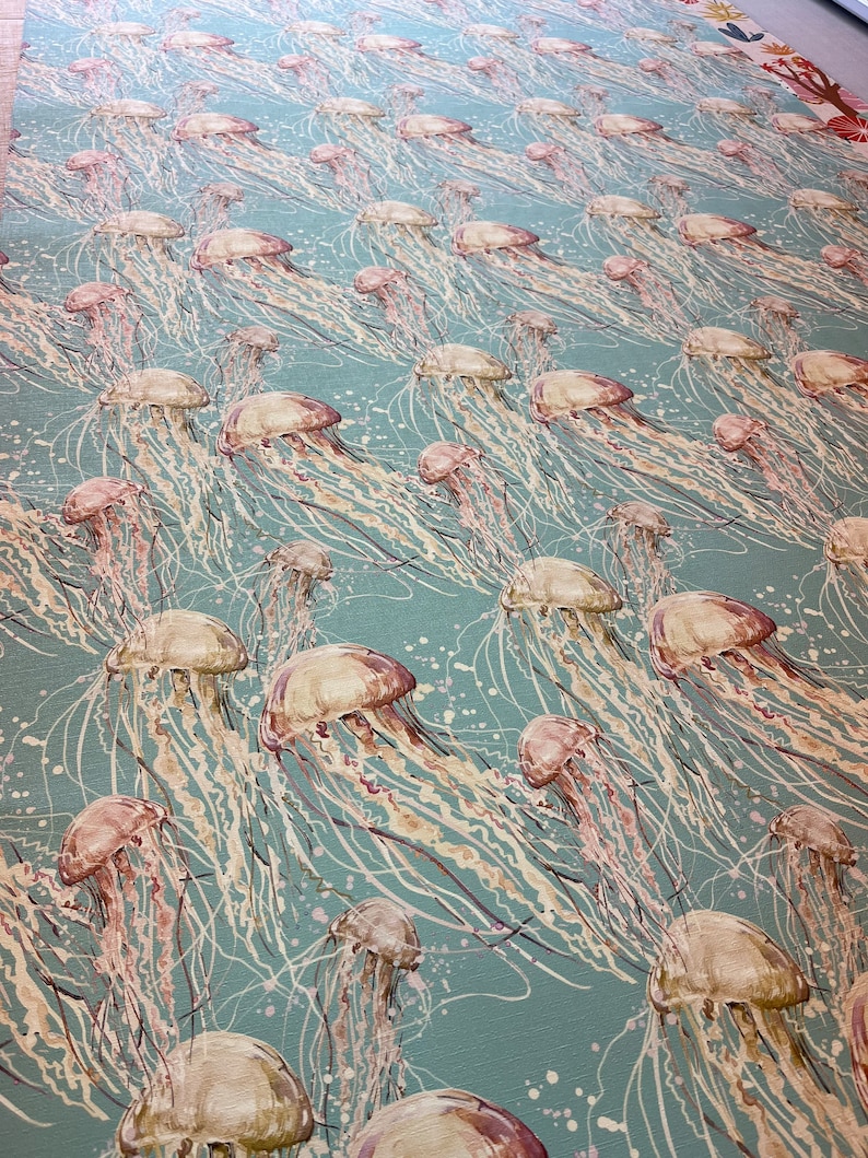 May include: A teal blue background with a repeating pattern of white and pink jellyfish. The jellyfish have long, flowing tentacles.