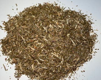 May include: A pile of dried, chopped herbs, primarily green and brown in color, against a white background. The herbs appear to be cut into small pieces, suggesting they are for culinary or medicinal use. The texture is rough and natural.