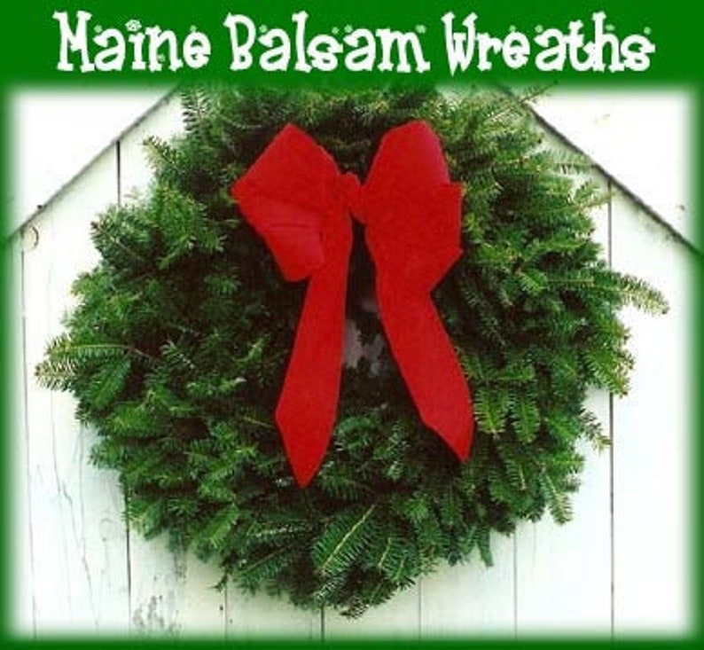 May include: A fresh green balsam fir wreath with a vibrant red bow. The wreath is displayed against a white wooden background, with the text "Maine Balsam Wreaths" at the top.