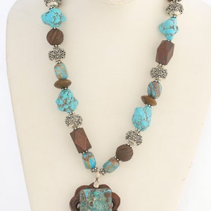 turquoise nuggets, carved wooden beads, ornate silver toned beads, carved jade pendant with a slab of magnasite in the middle
