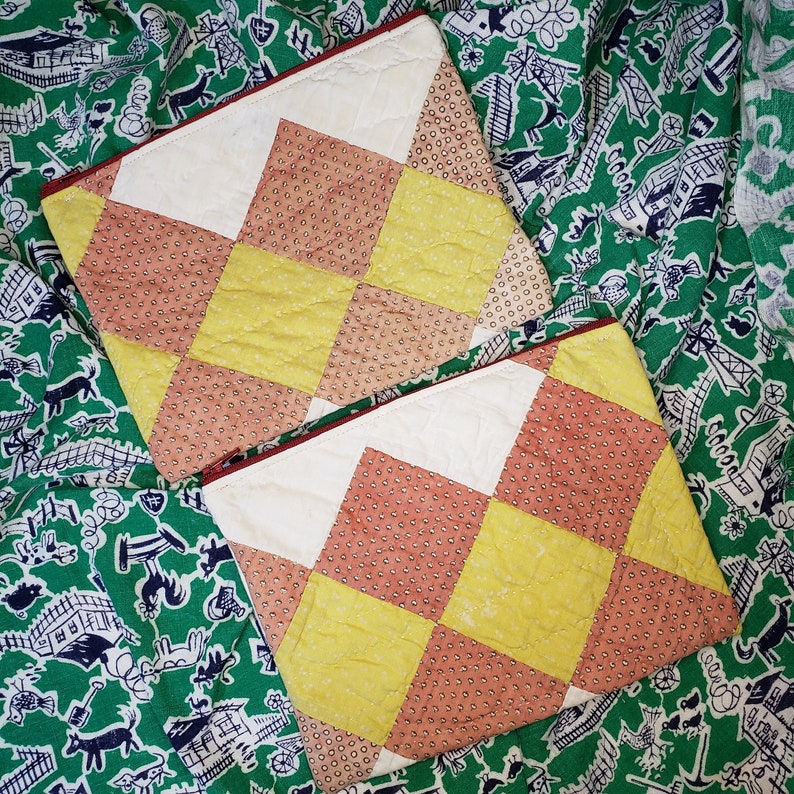 May include: Two quilted fabric squares with a checkered pattern in shades of yellow, red, and white. The squares are made of a soft, textured fabric and have a vintage aesthetic.