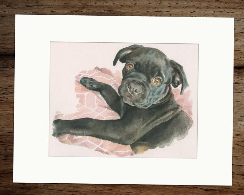 Puede incluir: Una pintura de acuarela de un cachorro negro con ojos marrones, acostado sobre una manta de estampado rosa y blanco. El cachorro est&aacute; mirando directamente al espectador.