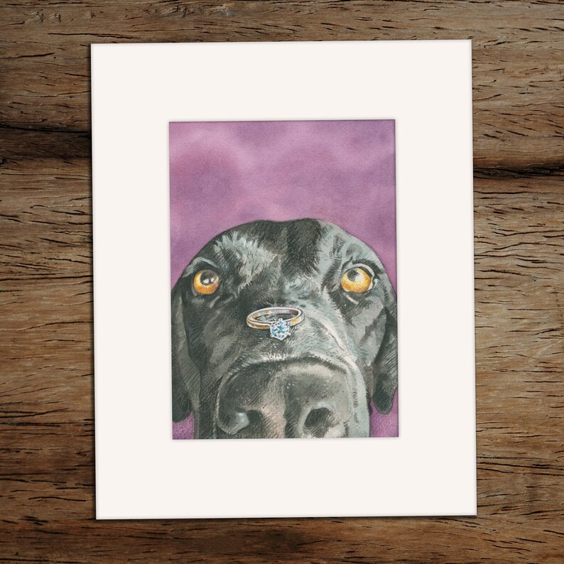 May include: A black dog with a ring on its nose. The dog is looking up at the camera with a curious expression. The ring has a large diamond in the center.