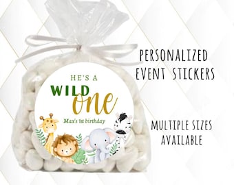 Peut inclure: Un sac en papier blanc avec un autocollant rond qui dit "He's a Wild One" en lettres vertes et dorées. L'autocollant présente également une illustration de girafe, de lion, d'éléphant et de zèbre. Le texte "Max's 1st birthday" est imprimé sous le texte principal. L'autocollant est destiné aux autocollants d'événements personnalisés et est disponible en plusieurs tailles.