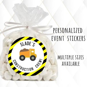 May include: A white favor bag with a yellow and black construction themed sticker. The sticker has a cartoon dump truck and the text "Slade's Construction Crew!"
