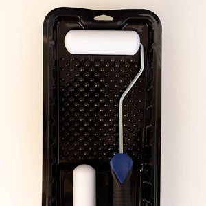 May include: A black paint roller tray with a white foam roller and a blue and black roller handle.
