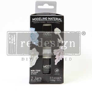 May include: Two jars of white modeling material in a black box with the text "Modeling Material" and "2 Jars" on the front. The box also includes the text "Non-Toxic" and "3.5 oz each (100g)".