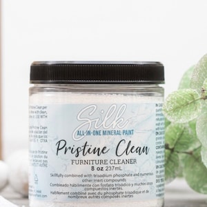 May include: A white jar with a black lid and a blue label that says "Silk All-in-One Mineral Paint Pristine Clean Furniture Cleaner 8 oz 237mL". The label also includes instructions for using the cleaner in English, Spanish, and French.