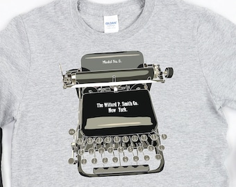 May include: A gray t-shirt with a black and white illustration of a vintage typewriter. The typewriter has the text "The Wizard P. Smith Co. New York" on it.