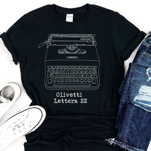 May include: Black t-shirt featuring a white outline of an Olivetti Lettera 22 typewriter. The text "Olivetti Lettera 22" is printed below the typewriter.