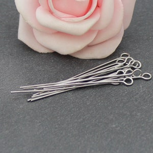 Può includere: Un mucchio di spilli per la testa argentati con un piccolo anello all'estremità. Gli spilli sono lunghi circa 2,5 cm.