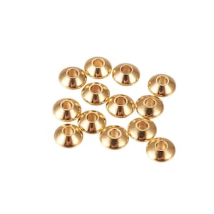 Op de afbeelding: Een verzameling goudkleurige metalen kralenkapjes. Elke dop is cirkelvormig met een centraal gat en een uitlopende, conische vorm. De doppen zijn gerangschikt op een witte achtergrond en zijn geschikt voor het maken van sieraden en knutselen.