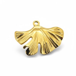 Op de afbeelding: Een goudkleurige metalen bedel in de vorm van een ginkgo-blad. De bedel heeft een gedetailleerd, getextureerd oppervlak met een kleine lus aan de bovenkant om aan een ketting of armband te bevestigen. Het bladontwerp heeft een natuurlijke, vloeiende vorm.