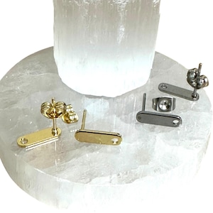 Könnte beinhalten: Drei Paar Ohrringe mit verschiedenen Metalloberflächen. Die Ohrringe sind oval geformt und haben einen Stiftverschluss.