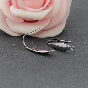 Peut inclure: Deux crochets d'oreille en argent avec une forme incurvée et une petite boucle à l'extrémité.