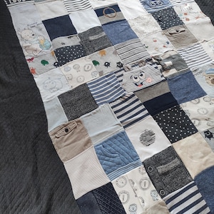 Könnte beinhalten: Eine Patchwork-Decke aus verschiedenen Stoffquadraten in Blau-, Weiß- und Grautönen. Die Decke enthält Streifenmuster, Punkte und Zeichentrickfiguren wie Winnie Puuh, mit dem aufgedruckten Text Little But Loud.