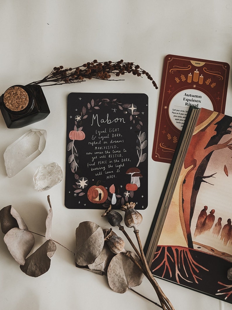 May include: A black card with white text and illustrations of pumpkins, mushrooms, and stars. The text reads "Mabon Equal LIGHT & equal DARK. reflect on dreams MANIFESTED, now comes the time to gel well RESTED. find PEACE in the DARK, knowing the light will leave it's MARK".