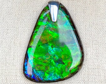 May include: A teardrop-shaped pendant with a silver bail and a green, iridescent gemstone. The gemstone has a mottled, layered appearance with shades of blue, green, and gold.
