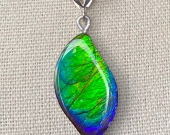 May include: A silver chain necklace with a green, blue, and purple iridescent gemstone pendant.
