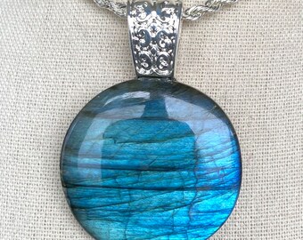 May include: A silver chain necklace with a round blue labradorite pendant. The pendant has a silver bail with an ornate design.