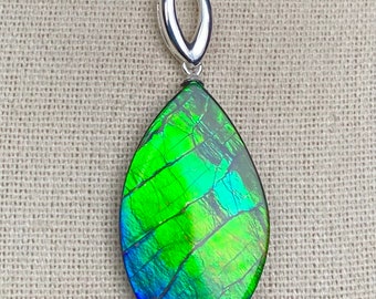 May include: A teardrop-shaped pendant with a green, blue, and iridescent opal gemstone. The pendant is attached to a silver chain.