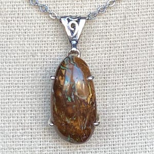 May include: A silver chain necklace with a brown and green opal pendant. The pendant is set in a silver bezel with four prongs.
