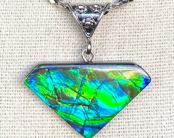 May include: A diamond-shaped pendant necklace with a silver chain. The pendant features a vibrant display of green, blue, and yellow colors. The pendant is attached to a decorative silver bail.