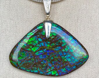 May include: A triangular pendant with a vibrant, iridescent gemstone, showcasing shades of green, blue, and brown. The pendant is suspended from a silver chain. The gemstone has a unique, cracked pattern, adding to its visual appeal. The pendant is a piece of jewelry.