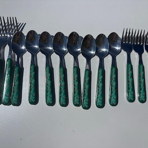 May include: A set of stainless steel flatware including forks and spoons with green handles. Each handle features a decorative pattern of white leaves and small red berries. The metal heads are polished silver, and the handles are uniform in design.