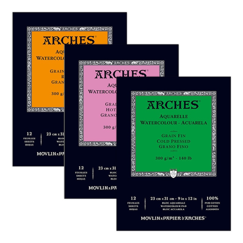 May include: Three packs of Arches watercolor paper. The packs are black with white lettering and a colored border. The top pack is orange and says "Aquarelle Watercolor - Grain Rough - 300 g/m2". The middle pack is pink and says "Aquarelle Watercolor - Grain Hot Pressed - 300 g/m2". The bottom pack is green and says "Aquarelle Watercolor - Aquarela - Grain Fin Cold Pressed - Grano Fino - 300 g/m2 - 140 lb".