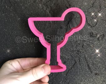 May include: Pink plastic cookie cutter shaped like a margarita glass with a lime wedge on the rim.