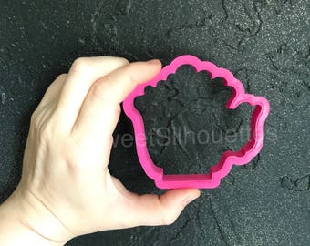 May include: A pink plastic cookie cutter shaped like a teapot with a handle and a spout.