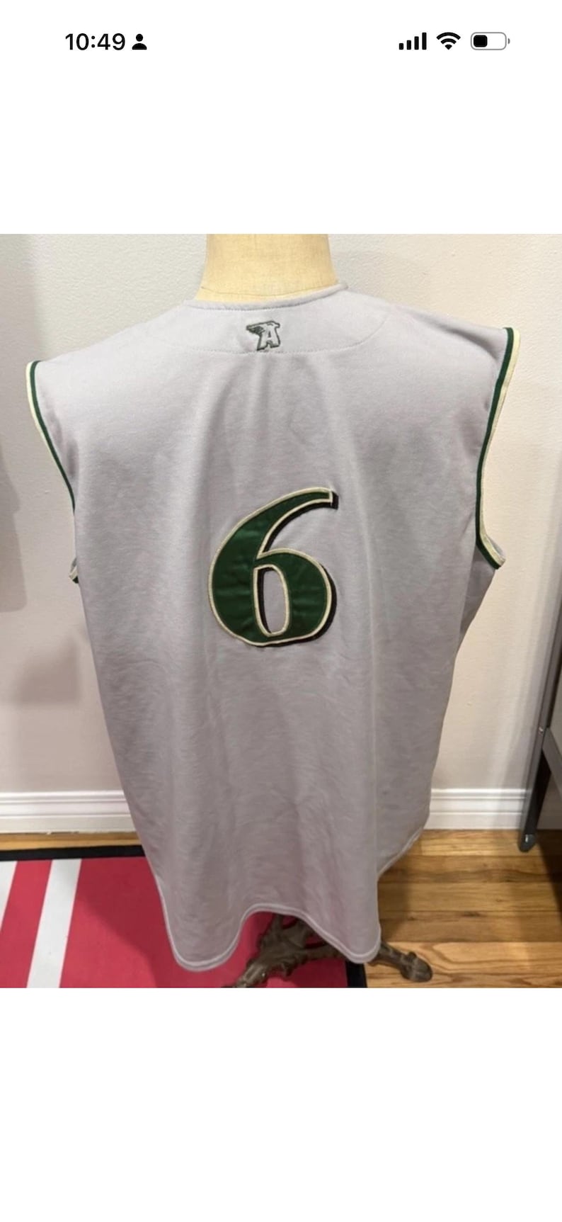 Op de afbeelding: Grijs mouwloos shirt met het nummer 6 in groen en wit. Het shirt heeft groene biezen en een logo op de bovenrug. Het shirt wordt op een mannequin getoond.