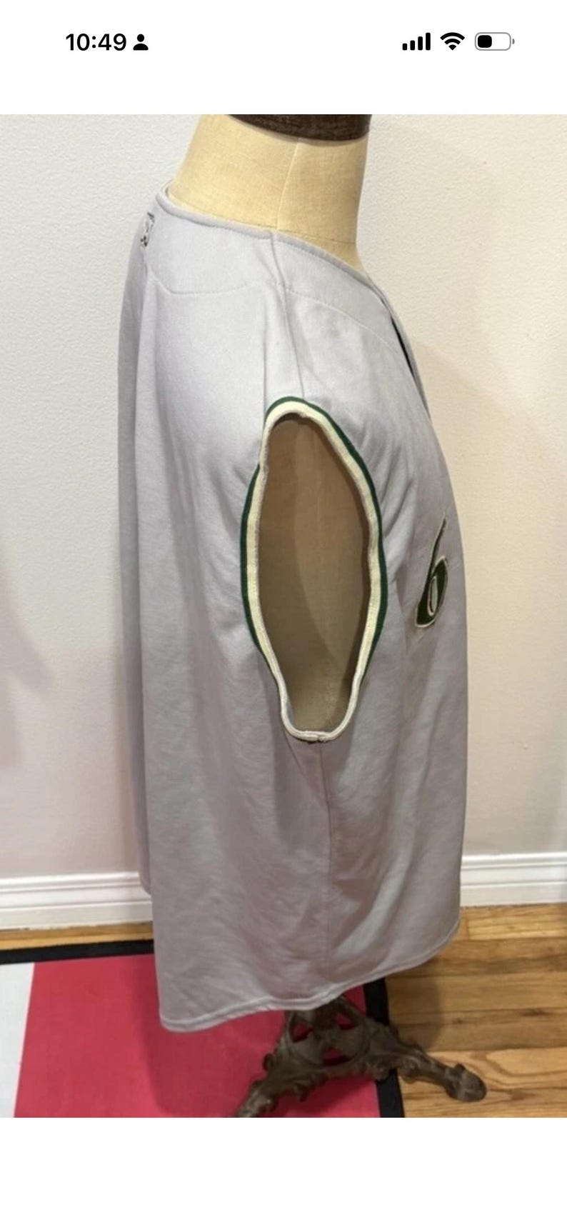 Op de afbeelding: Een lichtgrijs honkbalshirt met groen-witte randen op de mouwopeningen. Het shirt heeft een nummer 6 patch op de mouw. Het shirt wordt op een mannequin getoond.