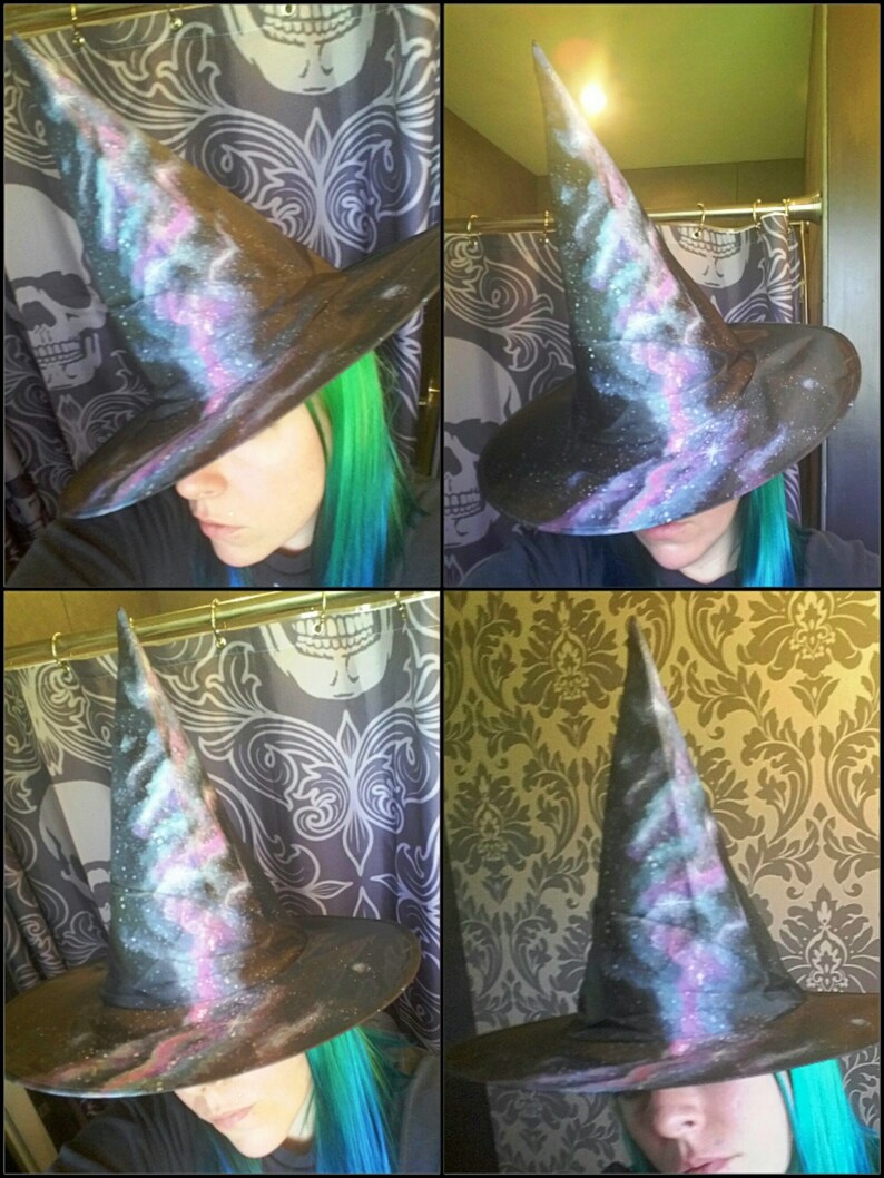 May include: A black witch hat with a galaxy print. The hat has a tall pointed crown and a wide brim. The galaxy print features shades of blue, purple, and pink.