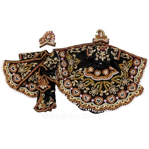 May include: A black beaded outfit for a religious figurine, featuring a skirt, top, and crown. The outfit is decorated with brown and white beads, pink accents, and floral patterns.