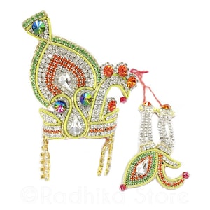 May include: A gold crown with red, orange, green, and white rhinestones. The crown has two long strands of rhinestones hanging from the bottom. The crown is on a white background.