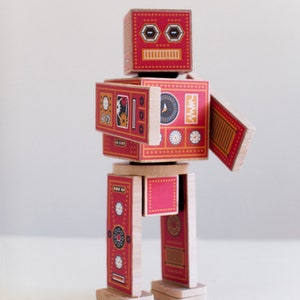May include: A red and yellow wooden robot toy with a face, arms, and legs. The robot has a variety of details on its body, including gears, dials, and other mechanical elements.