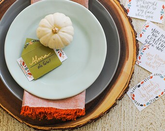 Puede incluir: Una mesa de Acción de Gracias con una calabaza blanca, un puesto de mesa y una pila de tarjetas con mensajes escritos a mano. Las tarjetas tienen un tema otoñal con colores naranja, marrón y verde. Las tarjetas dicen cosas como "¡Me haces sentir feliz cuando estás aquí!" y "¡Estoy muy contento cuando estás aquí!"