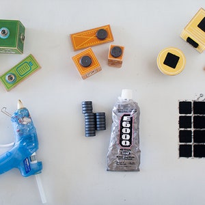 May include: A collection of craft supplies for making magnetic blocks. The supplies include wooden blocks, magnets, glue, adhesive squares, and a hot glue gun.