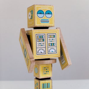 May include: A yellow wooden robot toy with blue and green details. The robot has a face with two blue eyes, a striped mouth, and a striped antenna. The robot's body is made up of several blocks with different patterns and designs.