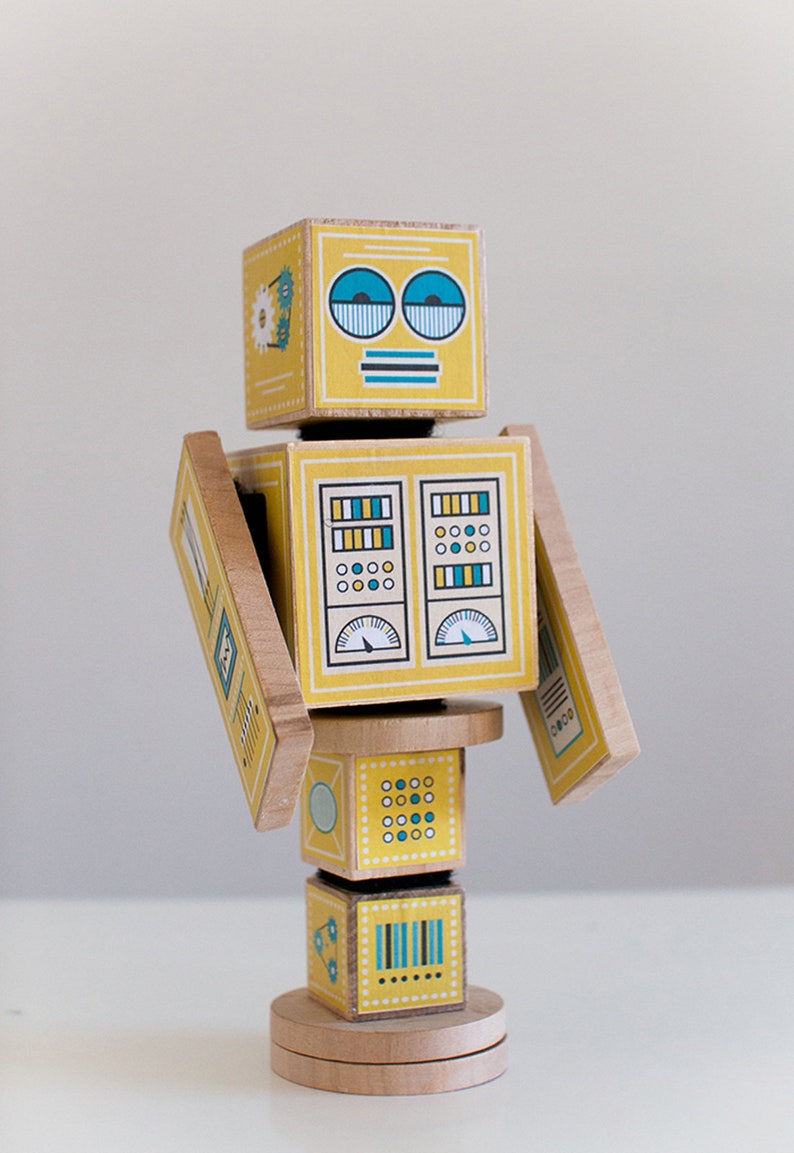 May include: A yellow wooden robot toy with blue and green details. The robot has a face with two blue eyes, a striped mouth, and a striped antenna. The robot's body is made up of several blocks with different patterns and designs.
