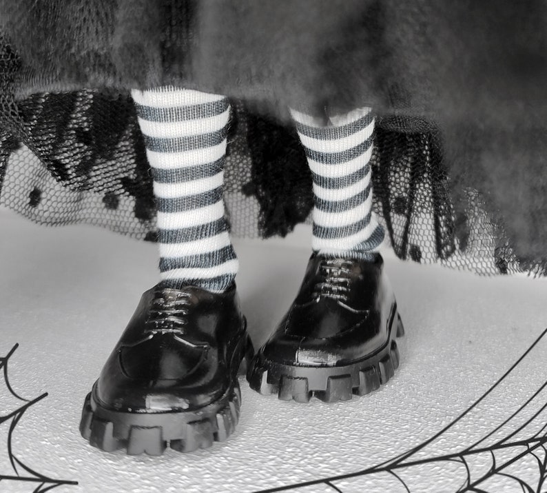 May include: Black and white striped socks with black leather shoes with thick white soles. The shoes have a lace-up design.
