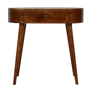 May include: An oval-shaped wooden side table in a mid-century modern style. It features a single drawer with a round metal knob. The tapered legs are angled, and the wood has a warm, brown finish. The table is approximately 76 cm high.