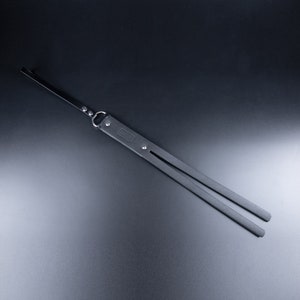 May include: A black leather camera strap with a metal ring and a small rectangular tag with the word "Camera" printed on it.