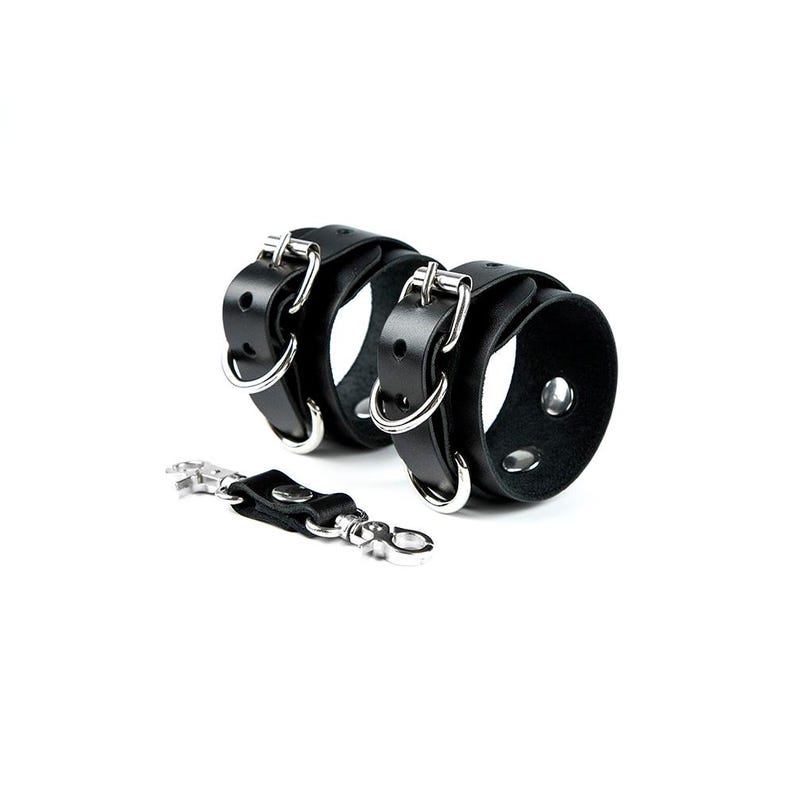 May include: Black leather wrist cuffs with silver buckles and a matching key chain.