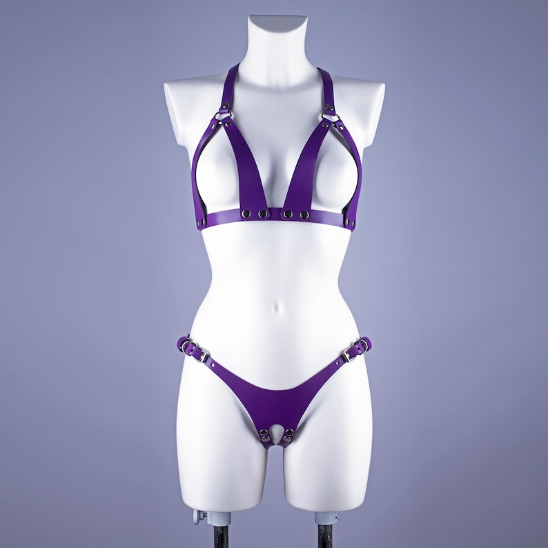 May include: Purple leather lingerie set with a halter top and a thong bottom. The set features multiple straps and buckles.
