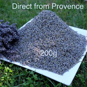 Può includere: Un piatto quadrato bianco contenente un grande mucchio di boccioli di lavanda essiccati viola e un mazzetto di steli di lavanda essiccati. Il testo Direct from Provence e 200g è stampato sull'immagine. La lavanda è di colore viola scuro.